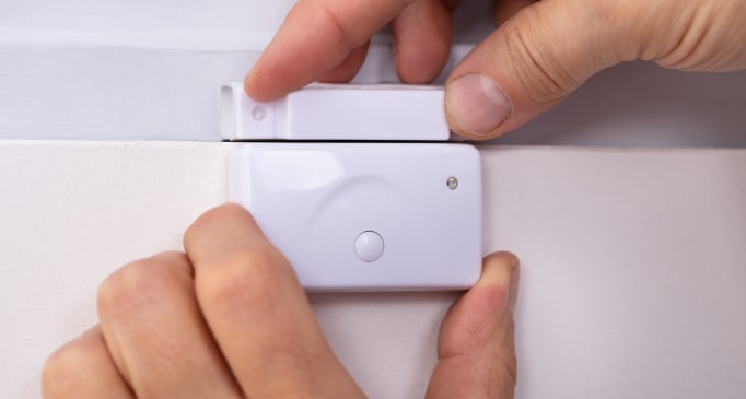 Hands installing door alarm sensor