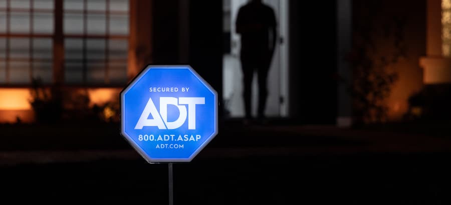 Bright ADT home security sign in yard of a home after dark.